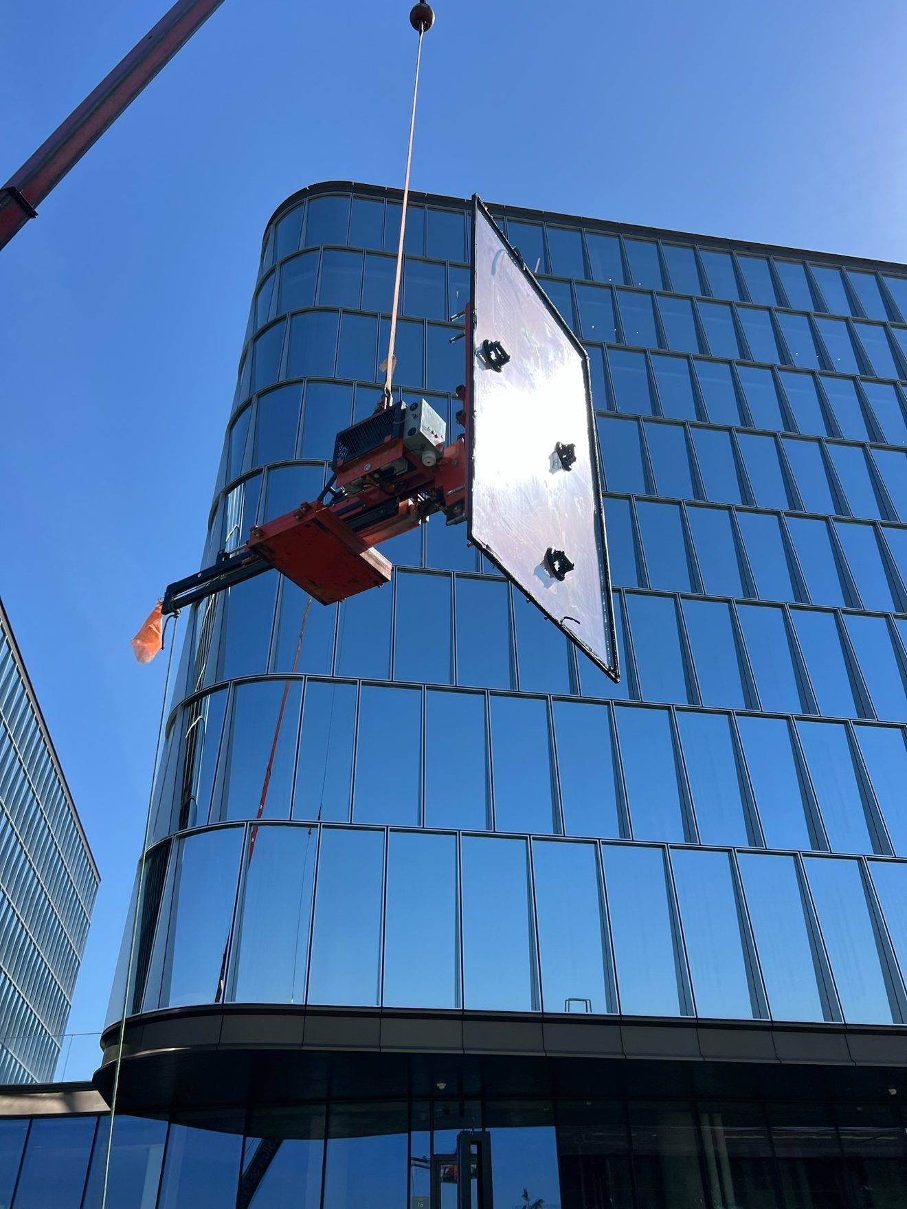 Panel setting by crane — glass panel on a curved building
